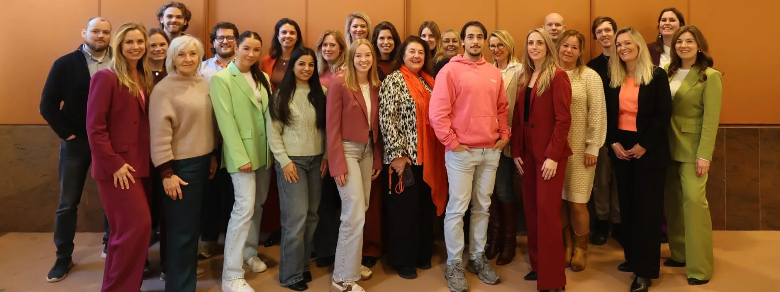 The artra team posing together in front of an orange wood-panelled wall