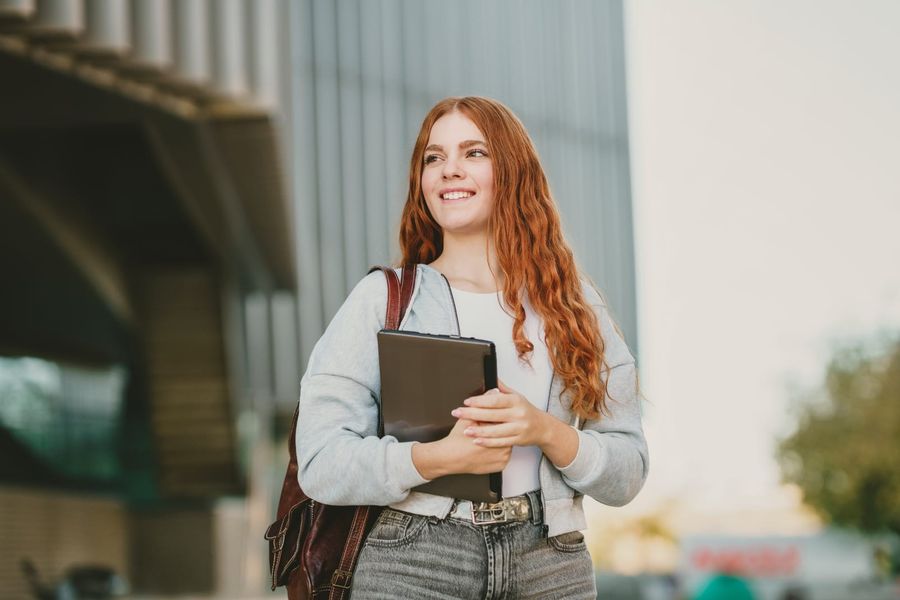 Lächelnde Person mit einem Tablet auf dem Campus