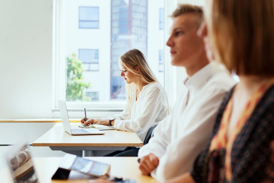 Kandidatinnen und Kandidaten an Tischen in einem hellen Klassenraum