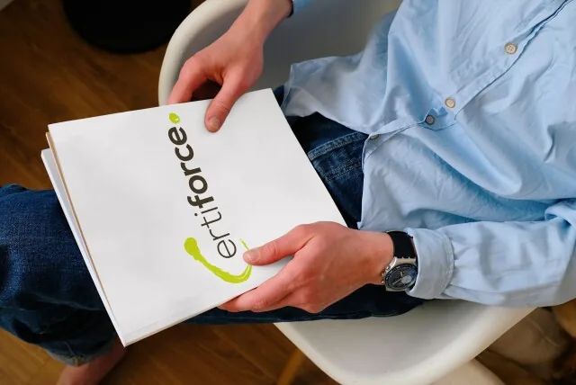 Eine sitzende Person hält eine Mappe mit dem Logo von Certiforce