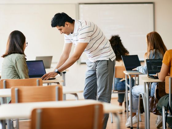 Docent die het werk van een student beoordeelt op een laptop