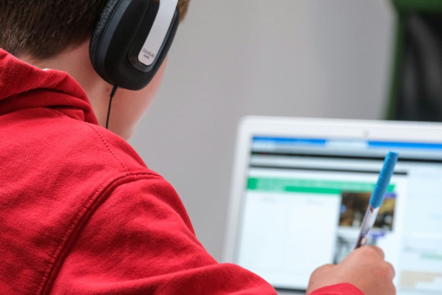Leerling met koptelefoon aan het werk achter een laptop