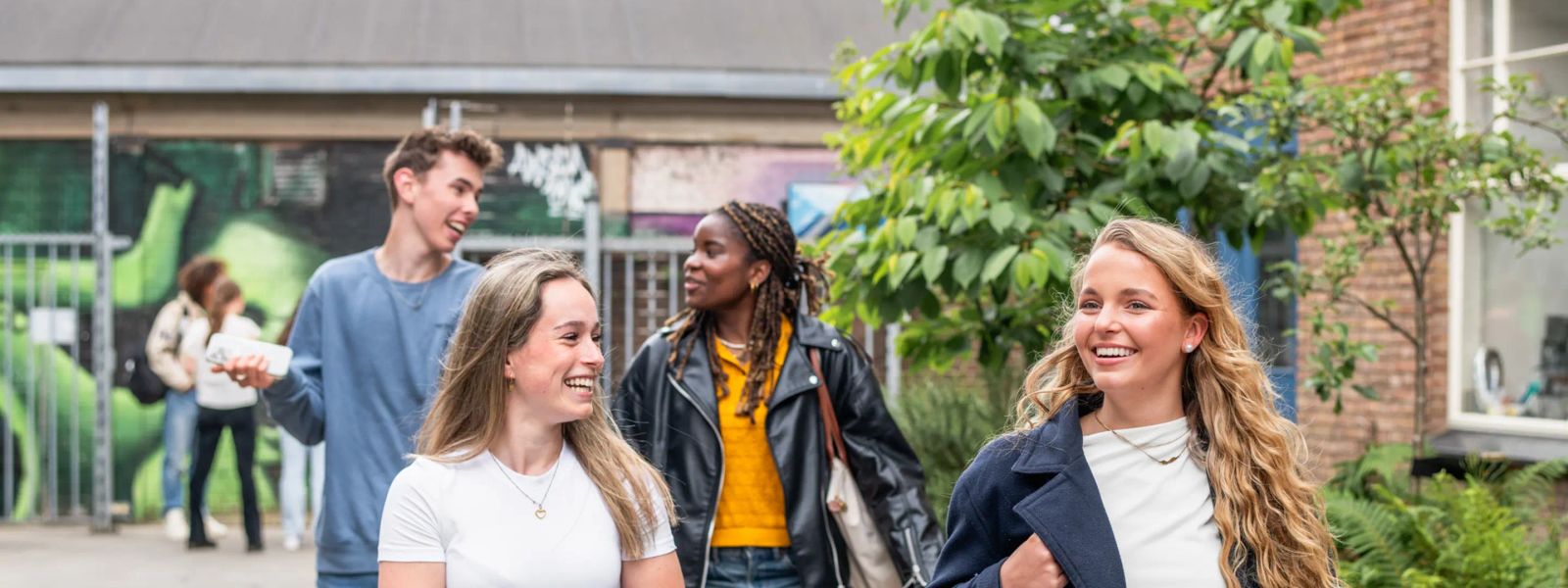 Studierende gehen draußen auf dem Campus von MBO Amersfoort und unterhalten sich