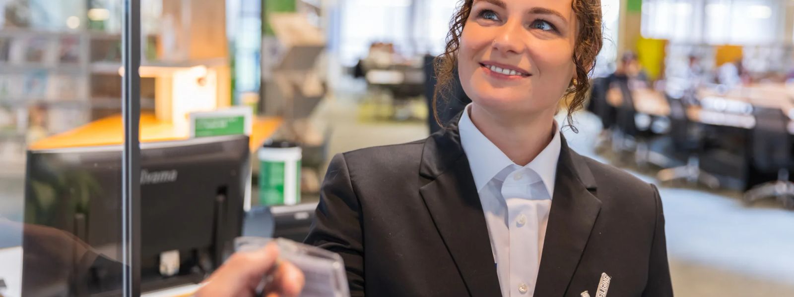 A security officer in uniform being handed an identity card at a reception desk
