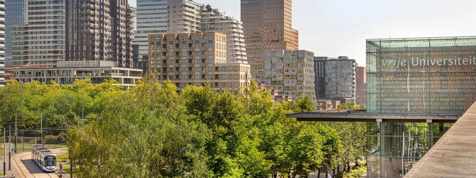 Die Glasfassade der Vrije Universiteit Amsterdam mit der Skyline der Zuidas dahinter